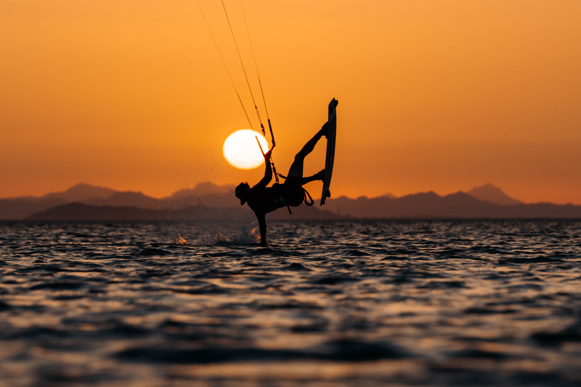 Kiteboarder silhouetted against the setting sun on the Red Sea